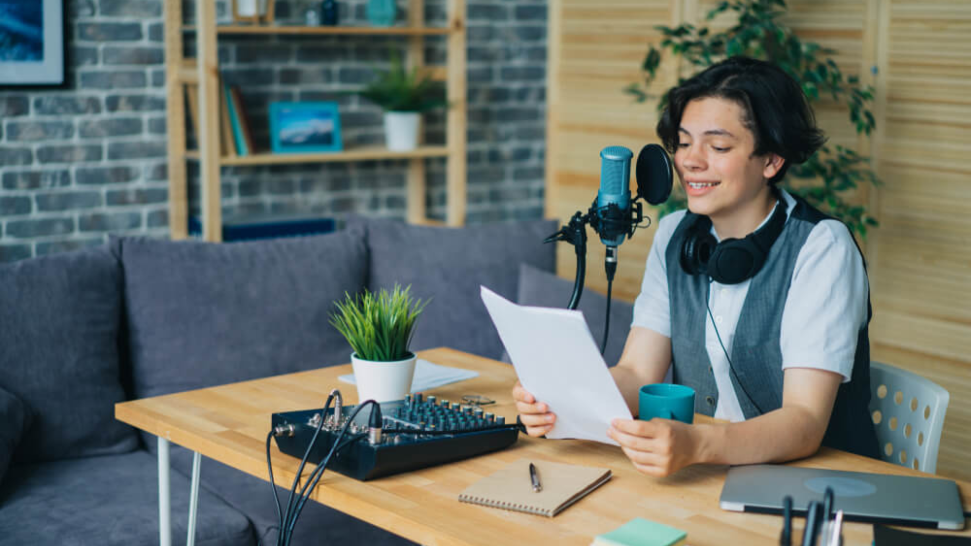 Person at home desk with podcast microphone setup reading script.