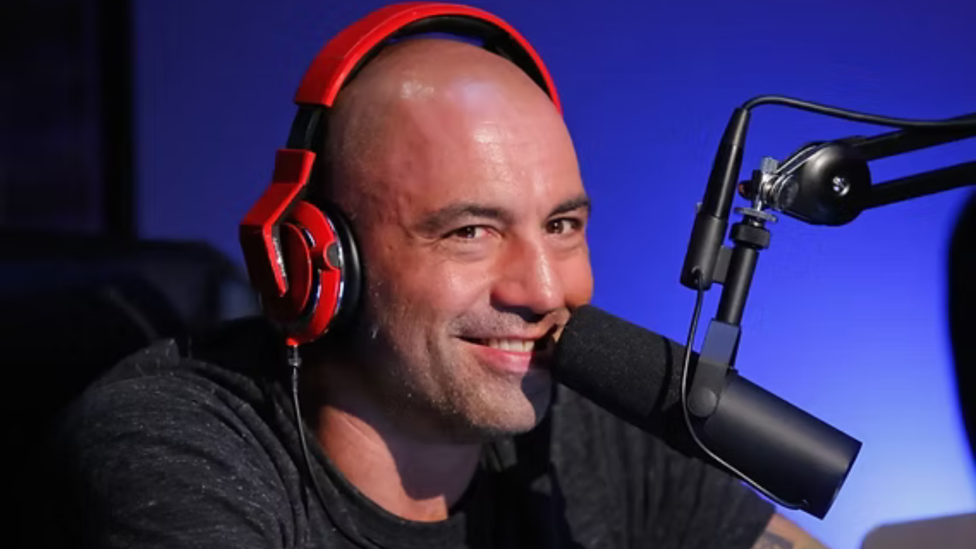 A person podcasting with red headphones and a microphone.